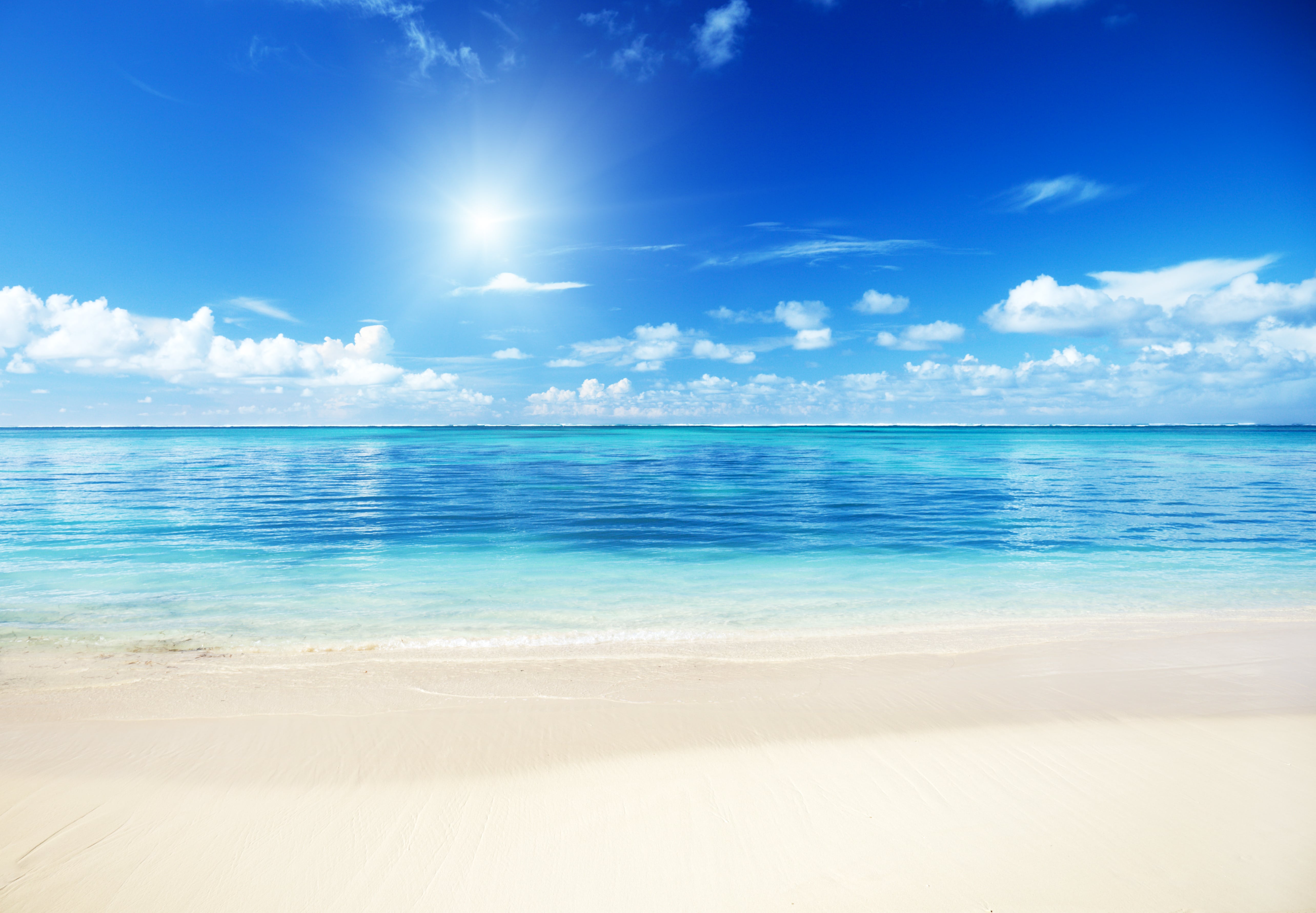 Direkt am Meer liegt eine Hotelanlage mit einer Poollandschaft zwischendrin immer wieder grüne Bäume und viele Sonnenschirme.